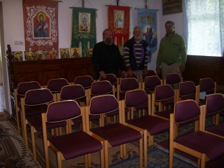 Pfarrer Coca (links) in het kerkzaaltje met de stoelen van Monuta 